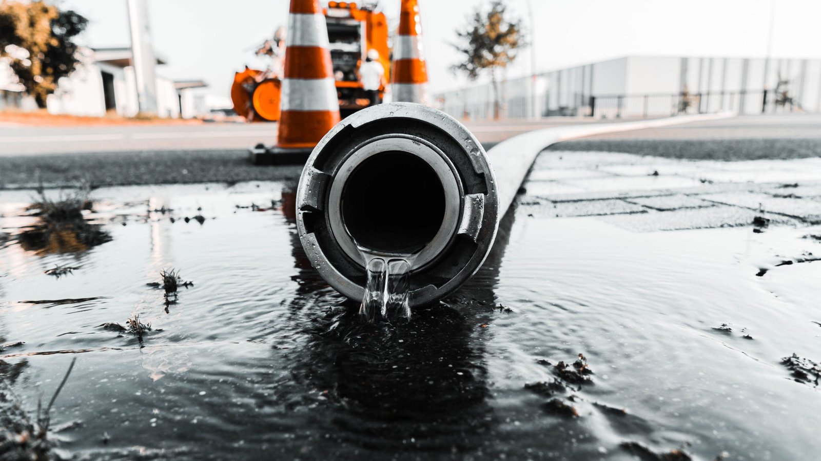 A selective closeup shot of a gray pipe with water coming out its hole